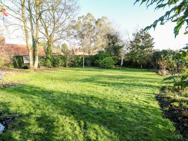 A garden with grass trees shrubs and a hedge at The Ramblers Annex in Mattishall