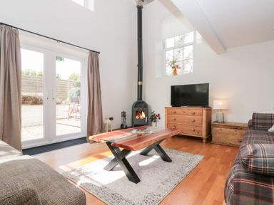 A living room with a wooden coffee table a fireplace a TV on a dresser and sofas at Old Chapel in Cloughton