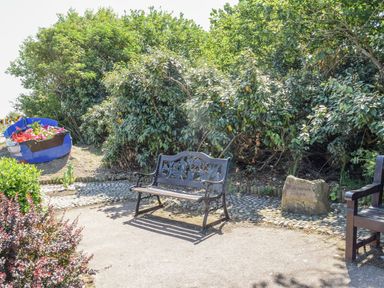A garden bench and a boat planter with flowers beside bushes at 20 Siesta Mar in Mundesley