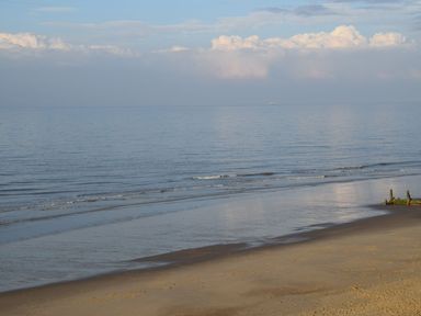 A sandy beach with calm sea waves and a cloudy sky at 20 Siesta Mar in Mundesley