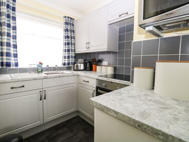 A kitchen with white cabinets a sink toaster kettle microwave and canisters on counters at 20 Siesta Mar in Mundesley