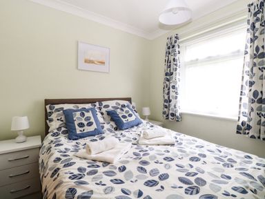 A bedroom with a bed covered in a leaf-patterned duvet and matching curtains at 20 Siesta Mar in Mundesley