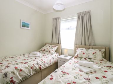A bedroom with two single beds floral bedding nightstand between beds with lamp at 20 Siesta Mar in Mundesley