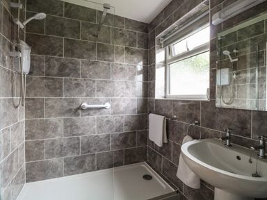 A bathroom with a walk in shower sink and window at 20 Siesta Mar in Mundesley