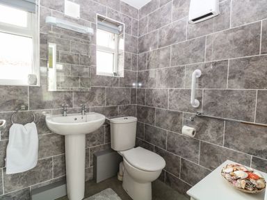 A bathroom with a pedestal sink toilet mirror and towel ring with seashell decorations at 20 Siesta Mar in Mundesley