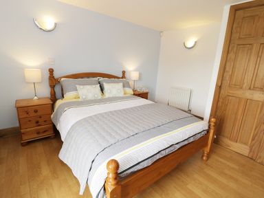 A bedroom with a wooden double bed two bedside tables with lamps and a wooden door at The Annex @ Garden House in Prudhoe near Newcastle