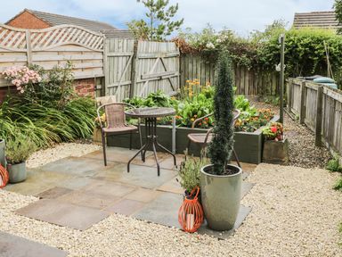 A garden patio with two chairs and a table surrounded by plants and wooden fences at The Annex @ Garden House in Prudhoe near Newcastle