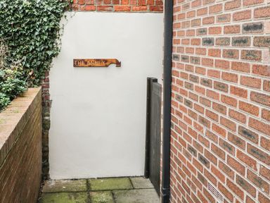 A narrow outdoor passage with brick walls and a wooden sign saying The Annex at The Annex @ Garden House Prudhoe near Newcastle
