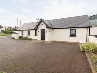 A front view of a white cottage with a black door and roof at Laharn Cottage in Killorglin County Kerry