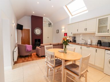 A kitchen with a dining table and chairs and a living area with sofas and a fireplace at Laharn Cottage in Killorglin County Kerry