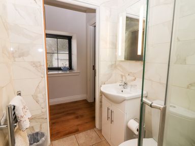 A bathroom with a sink cabinet mirror toilet and glass shower door at Laharn Cottage in Killorglin County Kerry