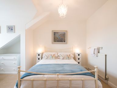 A bedroom with a bed and two bedside tables with lamps at Spiral View in Perranporth