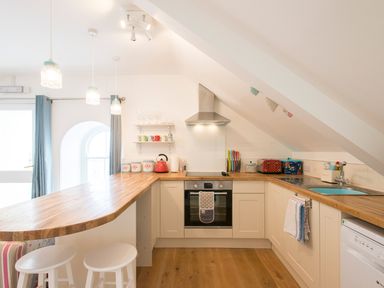 A kitchen with wooden countertops a stove an oven and stools at Spiral View in Perranporth