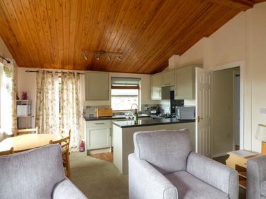A kitchen and dining area with wooden ceiling and grey armchairs at South Lodge in Kendal