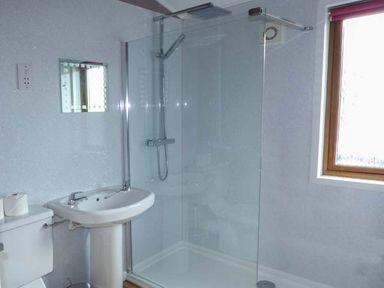 A bathroom with a toilet sink and a glass shower enclosure at South Lodge in Kendal