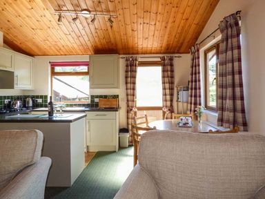 A kitchen and dining area with a round table chairs and curtains at North Lodge in Kendal