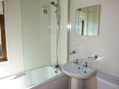 A bathroom with bathtub shower combination sink mirror and toilet at North Lodge in Kendal