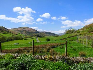 A green countryside landscape with hills fences and a blue sky at North Lodge in Kendal