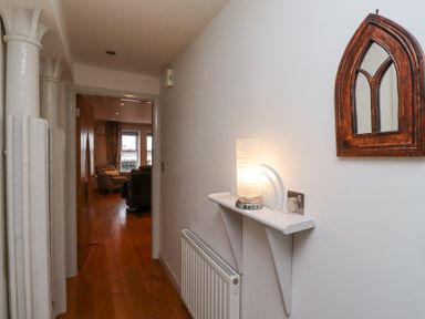 A hallway with wooden floor a radiator a wall-mounted shelf with a lamp and a wooden framed mirror at 6 Mill Wharf in Berwick-upon-Tweed