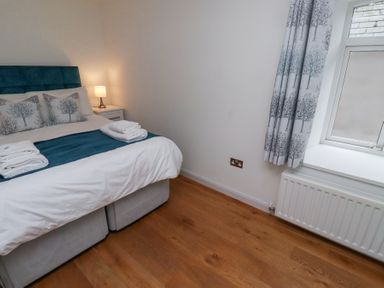 A bedroom with a double bed bedside table lamp window and patterned curtains at 6 Mill Wharf in Berwick-upon-Tweed