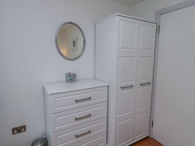 A white chest of drawers and a white wardrobe with a round mirror above the chest of drawers at 6 Mill Wharf in Berwick-upon-Tweed