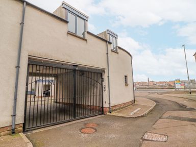 A gated parking area next to a curved building with two windows at 6 Mill Wharf in Berwick-upon-Tweed