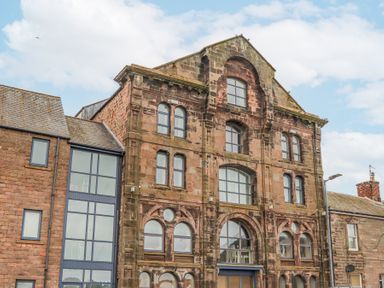 The exterior of a multi story stone building with large windows and adjacent smaller buildings at 6 Mill Wharf in Berwick-upon-Tweed