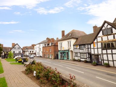 A street with historic half timbered buildings and benches along a paved pathway at Garden View in Malvern