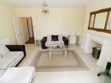 A living room with two sofas a glass coffee table a rug a white fireplace and a large mirror at Garden View in Malvern