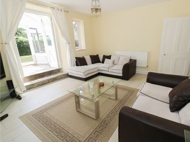 A living room with two sofas a glass coffee table and an open door leading outside at Garden View in Malvern