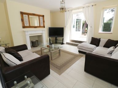 A living room with two sofas a glass coffee table a TV and an open door to a garden at Garden View in Malvern