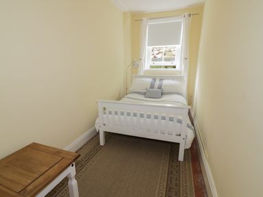 A small bedroom with a bed, side table, window, and floor lamp at Garden View in Malvern
