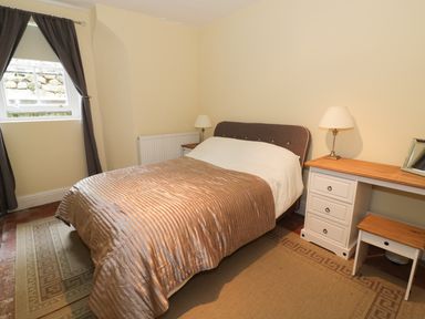 A bedroom with a bed a desk lamp and a window with curtains at Garden View in Malvern