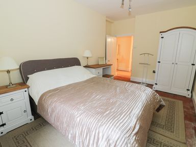 A bedroom with a bed a wardrobe bedside tables lamps and an open door at Garden View in Malvern