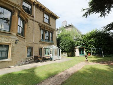 An outdoor garden area with a stone house, patio furniture, a small greenhouse, a playhouse, and a swing set at Garden View in Malvern