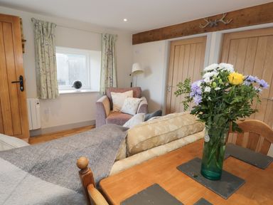 A living room with a floral bouquet on the table and chairs at The Granary Loft in Bardsea