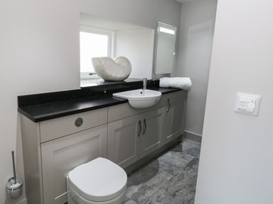 A bathroom with a toilet sink countertop and mirror at The Granary Loft in Bardsea