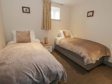 A bedroom with two single beds a nightstand and a window at The Granary Loft in Bardsea