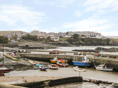 A small harbor with various boats docked and houses on a hillside in the background at Harbour View in Cemaes Bay