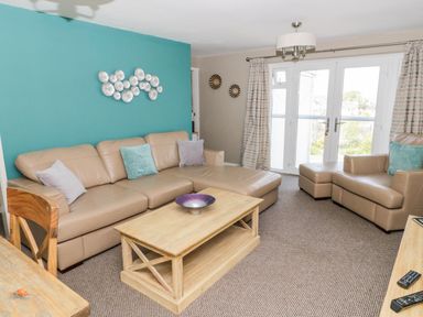 A living room with beige leather sofas and a wooden coffee table at Harbour View in Cemaes Bay