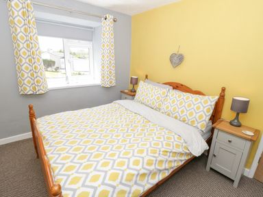A bedroom with a double bed and patterned bedding beside two bedside tables with lamps at Harbour View in Cemaes Bay