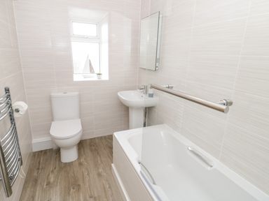 A bathroom with a toilet sink bathtub and a window at Harbour View in Cemaes Bay