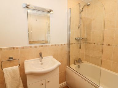 A bathroom with a sink a mirror and a bathtub with a shower at Coniston Number 9 in White Cross Bay