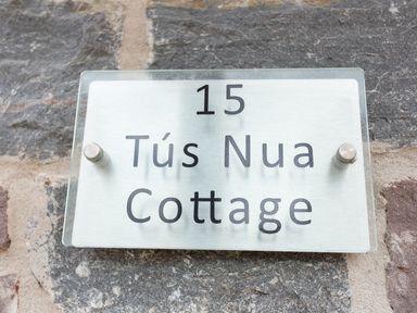 A house number sign reading 15 Tus Nua Cottage mounted on a stone wall at Tus Nua Cottage in Carhampton