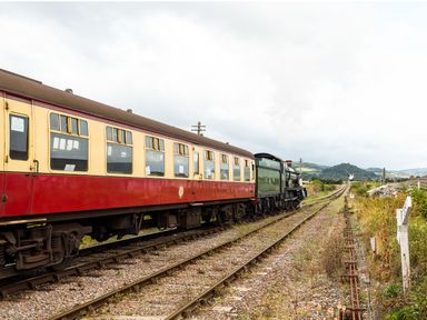 A vintage train on railway tracks in a rural area with hills in the background at Tus Nua Cottage in Carhampton