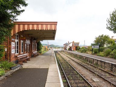 A train station platform with benches and a small brick building next to railway tracks at Blue Anchor
