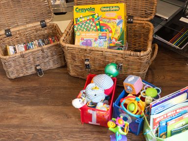 Baskets and containers with toys books and board games on a wooden floor at Tus Nua Cottage in Carhampton