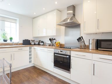 A kitchen with white cabinets wooden countertops a stainless steel stove and oven and kitchen appliances at Tus Nua Cottage in Carhampton