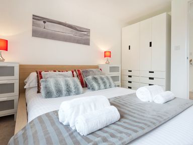A bedroom with a double bed pillows bedside tables with lamps and a wardrobe at Tus Nua Cottage in Carhampton