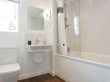 A bathroom with a toilet sink mirror bathtub and shower at Tus Nua Cottage in Carhampton
